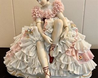 Dresden Ballerina tying shoes while sitting.