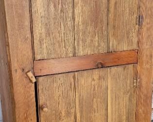 Primitive wooden cupboard with wooden latch closure on screened porch