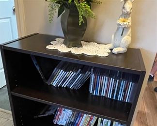 small bookcase, DVDs/CDs, books, floral arrangement, rabbit figurine
