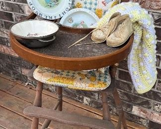 Vintage wooden high chair with crochet blanket, walking shoes, baby dishes