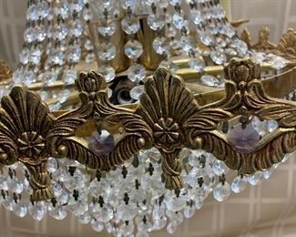 LOT 021- Marked "MADE IN SPAIN" Hollywood regency chandelier in the style of Swarovski AS-IS. There are bent sockets, damage to the metal at the sockets and prism loss. $575 