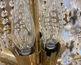 LOT 021- Marked "MADE IN SPAIN" Hollywood regency chandelier in the style of Swarovski AS-IS. There are bent sockets, damage to the metal at the sockets and prism loss. $575 