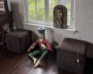 These are a pair of interesting object d'art: the seated figure and the wall figure are framed by the pair of ottomans.