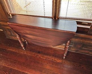 Narrow drop leaf table with carved legs.