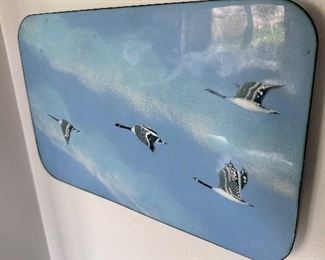 Enamel depiction of Canadian geese in flight.