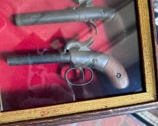 Framed antique boot guns.
