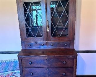 Glass front, fold out secretary bookcase with book matched veneer.