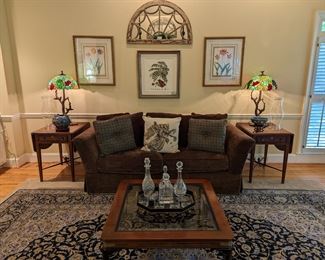 Asian influenced coffee table, w/beveled glass, by Gordon's, of Johnson City, TN, tole serving tray with crystal decanters, pair of Hekman drop-leaf banded mahogany side tables, down sofa by Isenhour, pair of Tiffany-style stained glass lamps, w/bird, branch bases, pair of nicely framed/matted botanical prints, by Soicher-Marin Fine Art, single hand-colored botanical print and arched wooden wall mirror (one of a pair).