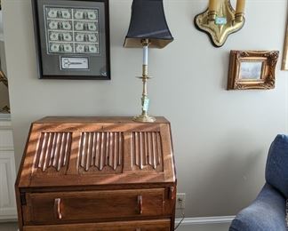 1930's "Linen Fold" oak drop-front desk, brass candlestick table lamp, framed dollar bills from his first attempt at amateur stripping and vintage brass 2-light wall-hung candelabra.