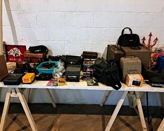 A table full of old cameras and projectors.  Kodak, Minolta, Bell and Howell. 
