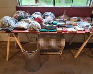 A table full of needlepoint and sewing supplies, including well priced bags of useful supplies and treats.  Bingo drum below table. 