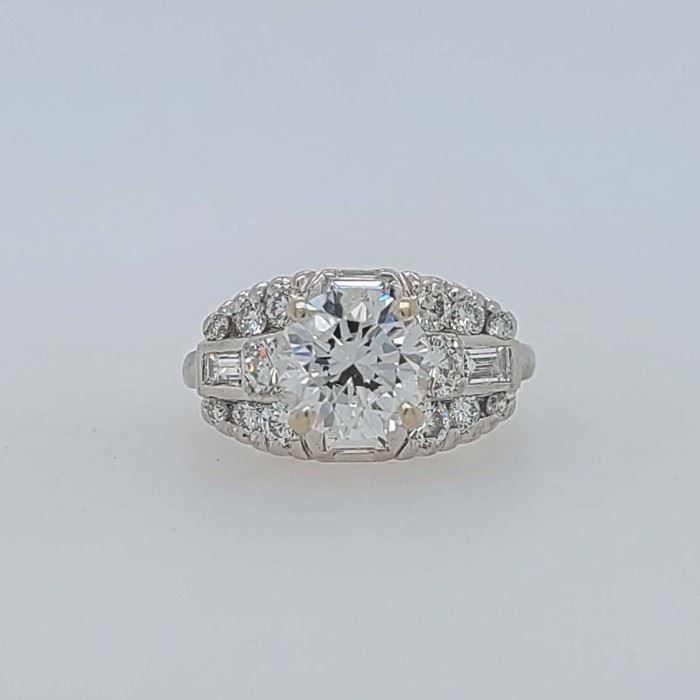 Very good condition. From Calhoun's: "One lady's 90% platinum 10% iridium ring containing the following stones: A) One round brilliant-cut diamond measuring 8.1x5.05mm and weighing approximately 2.20cts with a color of I and clarity of VS1, B) two round brilliant-cut diamonds measuring 3.35mm each and weighing approximately .20cts each with a color of F and clarity of VVS1, C) four baguette diamonds measuring 3.5x2.0mm each and weighting approximately .11cts each with a color of F and clarity of VVS1, D) four round brilliant-cut diamonds measuring 2.60mm each and weighing .07cts each with a color of F and clarity of VVS1, E) four round brilliant-cut diamonds measuring 2.30mm each and weighing .05cts each a color of F and clarity of VVS1, and F) four round brilliant-cut diamonds measuring 1.7mm each and weighing .02cts each a color of F and clarity of VVS1. Finger size: 6.5. Metal weight: 5.36 DWTs." Appraised in 2007 for $63,270.00 by a local jeweler, copy included with purchase. From 