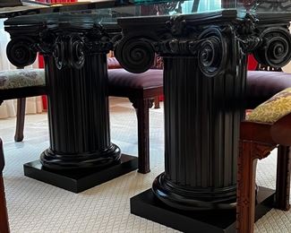 Two large black columns, supporting glass top dining table