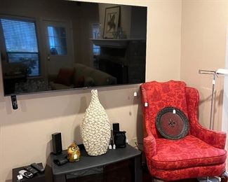 65 inch smart tv, red wing back chair and a TV stand plus lots of decor