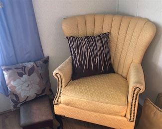 Yellow clamshell chair, pillows, footstool.