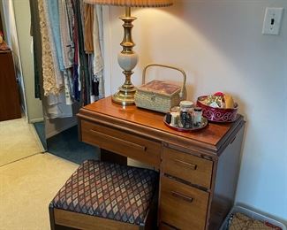 Singer sewing machine in cabinet with sewing stool, table lamp, and sewing notions