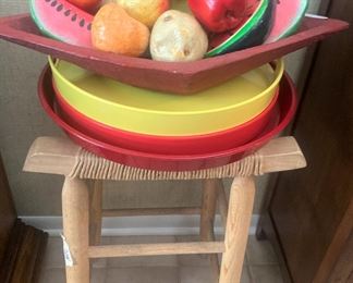 Single stool; colorful trays; bowl of fruit