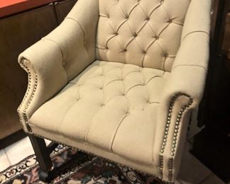 One of two tufted occasional chairs with railhead trim