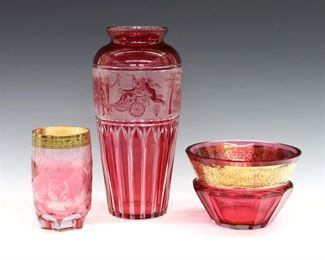 Three pieces of 20th century Moser faceted Cranberry glass.  Includes a vase, tumbler and bowl with etched decoration, two with Gilded detail.  Tumbler and bowl marked "Moser", vase unmarked.  Some surface wear, losses to Gilding, small flake to vase rim.  Up to 10" high.