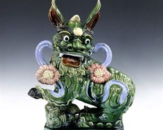 A Chinese Terracotta Foo Dog figure with Sancai glaze.  Some crazing, chip to toe and base, a few hairlines to glaze at base.  Approx. 15 x 7 1/2 x 19" high overall.  
