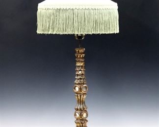 An early 20th century Spanish Colonial candlestick table lamp.  Antique Baroque style wooden candlestick stem and foot with inlaid mirror detail and Gilded finish, with a silk fringed shade.  Converted to use as an electric lamp, wear to patina with surface flakes, some cracks and losses to mirrors.  35" high.  