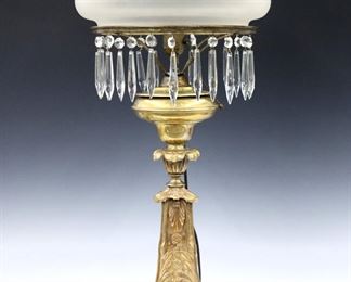 A 19th century American Astral lamp by Dietz Brothers & Co.,  New York.  Brass font on a foliate Gilt Bronze stem, with a frosted glass shade and pressed glass prisms.  Maker's mark at font.  Electrified with burner removed, chips to shade fitter, some prisms replaced with chips, several missing.  24" high overall.  
