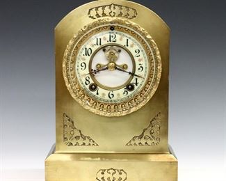 An early 20th century Ansonia "Hampshire" model mantel clock.   8-day time and strike movement with two part porcelain dial, Arabic numerals and visible escapement.  Cast Brass case with foliate decoration in relief.  Some surface wear to case, replaced pendulum bob, running when cataloged.  10 1/2" high.  
