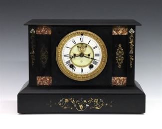A turn of the century Ansonia mantel clock.  8-day time and strike movement with two part porcelain dial, Roman numerals and visible escapement.  Black slate case with carved floral detail and inset marble panels.  Some surface wear and flakes to slate, running when cataloged.  12 3/4 x 6 x 9 1/4" high overall.  
