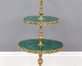 A 20th century French Bronze and Malachite dessert table.  Three graduated tiers in Gilded cast Bronze with circular Malachite shelves and reticulated Bronze edges on a tripod base with female masks and palm leaf detail.