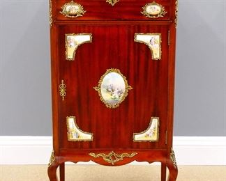 A 20th century French Louis XV style music cabinet.  Mahogany construction with Brass mounts and inset porcelain plaques, features a molded top with Brass gallery over a single drawer and lower door on short cabriole legs.  Original finish with some wear and surface scratches.  25 1/2 x 15 x 46" high overall.