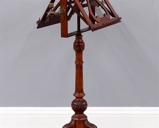 A turn of the century Victorian duet stand.  Mahogany construction with carved detail features an adjustable double sided music rack with Lyre design and Brass candleholders on a tall turned stem with fluted detail and tripod base with turned finial.  Older refinishing with some wear.  48" high.  