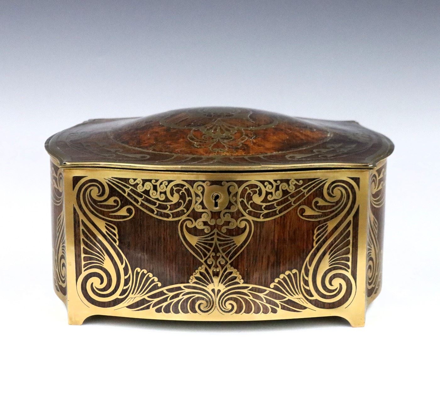 A turn of the century Erhard & Sohne Jugendstil inlaid box, c. 1905.  Fine Rosewood construction with domed Burl top and Brass inlay depicting scrolling florals in the Art Nouveau manner, within a Brass frame with short bracket feet.  Hinged top opens to reveal a single compartment with velvet lining.  