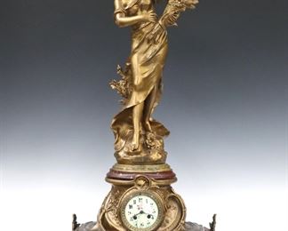 A turn of the century French figural mantel clock by Fritz Marti, Paris.  8-day time and strike movement with hand painted porcelain dial and Arabic numerals.  Cast Spelter case on a shaped Rouge Marble base with cast legs surmounted by a Spelter figure entitled "Reine des Pres" after Auguste Moreau. 