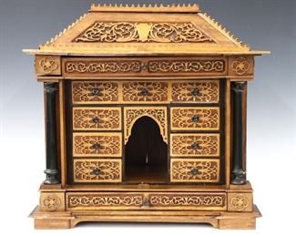 An early 20th century British Raj Period altar cabinet.  Mixed wood construction in the form of a temple with scrollwork overlay and lacquered columns on a bracket base.  Features an central altar niche and eight drawers. 