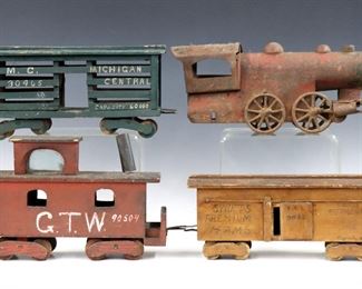 An early 20th century American Folk Art train set.  Cast Iron and wooden construction, includes a Cast Iron locomotive with four wooden cars, a wagon, a flatbed and tower with polychrome painted finish.  Original painted finish with wear, locomotive with significant rusting, minor damage.  