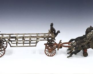 A turn of the century American Cast Iron fire wagon toy.  Includes two fireman on a ladder wagon drawn by three horses with worn polychrome painted finish. 