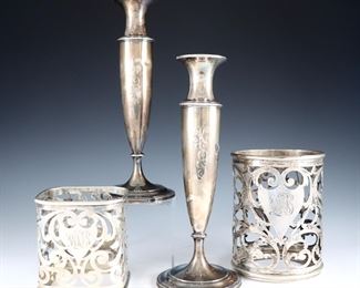 Four pieces of early 20th century American Sterling Silver.  Includes a pair of candlesticks by Whiting Manufacturing Co., and two floral overlay holders by George Henckel & Co.  Impressed marks.  18.99 troy ozs total.  Some surface wear, monogrammed, one candlestick with dent at side, the other with some distortion.  Up to 9" high.  