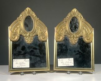 (2PC) PAIR AUSTRIAN MIRRORS  |  Pair of framed Austrian mirrors with smaller oval mirror in reserved pressed brass, decorated with scrollwork, wood backings. Dimensions: w. 7.5 x h. 12.5 in