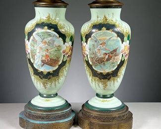 (2PC) PAIR PAINTED CERAMIC LAMPS  |  Each decorated with hand-painted scenes with an angel and baby, on shaped and reticulated brass bases. 