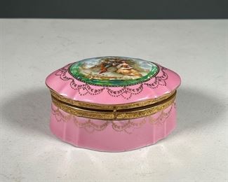 PAINTED PORCELAIN JEWLERY BOX |  German pink porcelain jewelry box of small size with gilt decoration, the lid hand painted with a courting scene, with floral decoration inside, the bottom marked "Made in Germany"