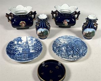 (7PC) BLUE & WHITE PORCELAIN |  Small table objects, including: a pair of cobalt blue bud vases made in Germany showing the old High School of Mt Kisco NY; two French vases with women; a small cobalt blue dish with floral design and gilt rim, and a pair of Liberty blue saucers depicting different colonial scenes. 