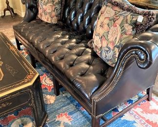 The tufted leather sofa has nail-head trim. (as is)