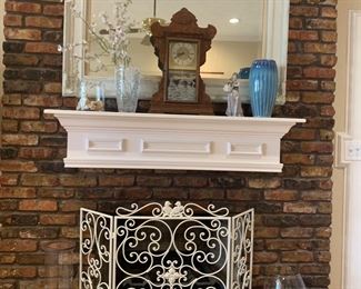 Sitting on the mantle is an amazing old clock and below it is a great old metal fireplace screen.