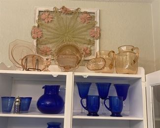 Blue glassware is in the vintage cabinet. Above the blue glass wear are nine pieces of pink depression glass.
