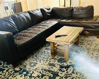 Leather sectional, rugs, coffee table made from antique wood.