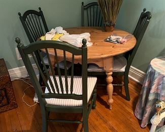 Pine round dining room table with four chairs.