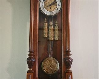 Vienna Regulator with Double Chime
A 3-weight Vienna regulator with matching brass face, weights and pendulum. Carved walnut case. 39L x 14W. Crown is 17W x 5 1/2 D. Glass front and sides. The unique chime provides the hour in one tone and each quarter hour in another. Quarter one is one chime, quarter two is two chimes, quarter three is three chimes and the hour is 4 chimes along with the hour number. Once known as a blind man’s clock, because you don’t have to look at this clock to know what hour it is. [Example: 2 o’clock is four chimes in one tone, and 2 chimes in the other] 4 quarters after 1! 
