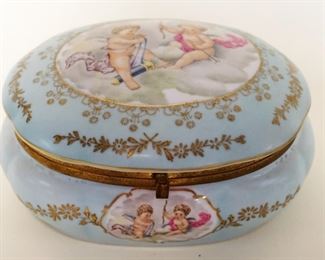 1127	PORCELAIN OVAL HINGED DRESSER BOX W/IMAGES OF CHERUBS & ROSE INTERIOR, APPROXIMATELY 5 IN X 7 IN X 4 IN HIGH
