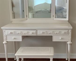 Antique White Vanity with Tri-Fold Mirror. Applied Carving Decorate Drawer Fronts and Center Mirror Crown.  Cane Bottom Matching Vanity Stool.                           Vanity: 30”H x 43”W x 19”D + Mirror: 28”H.                               Stool: 17”H x 22”W x 14”D