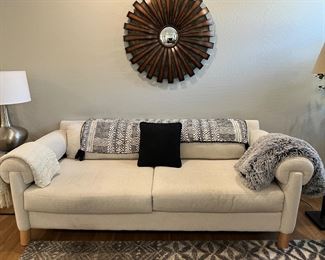 Living Spaces Sofa, Assorted Throws, Hammered Metal Table Lamp, Metal Starburst Mirror